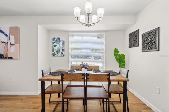 dining space with light hardwood / wood-style flooring and a chandelier