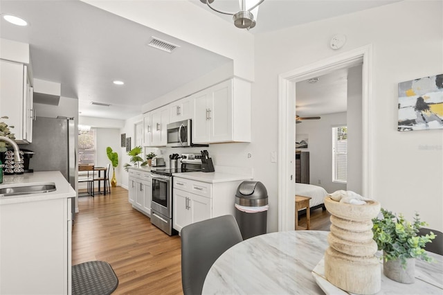 kitchen featuring white cabinetry, appliances with stainless steel finishes, sink, and light hardwood / wood-style floors