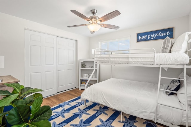 bedroom with wood-type flooring, ceiling fan, and a closet