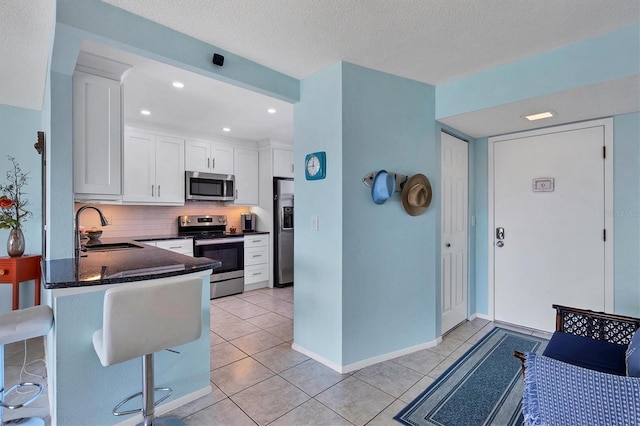 kitchen featuring sink, white cabinetry, appliances with stainless steel finishes, kitchen peninsula, and backsplash