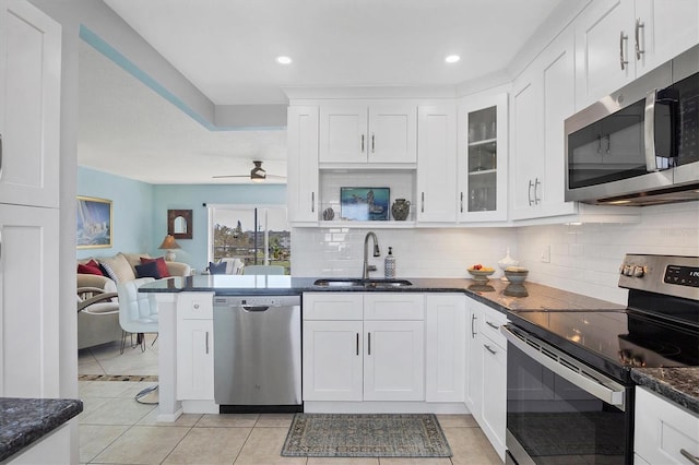 kitchen with appliances with stainless steel finishes, sink, dark stone countertops, and white cabinets