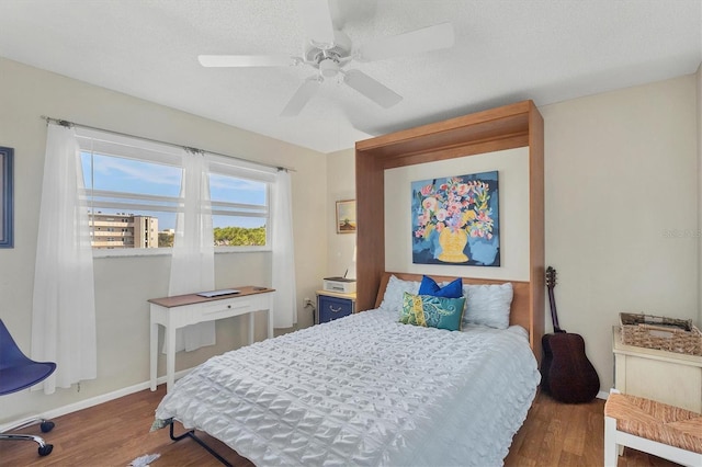 bedroom with dark wood-type flooring, ceiling fan, and a textured ceiling