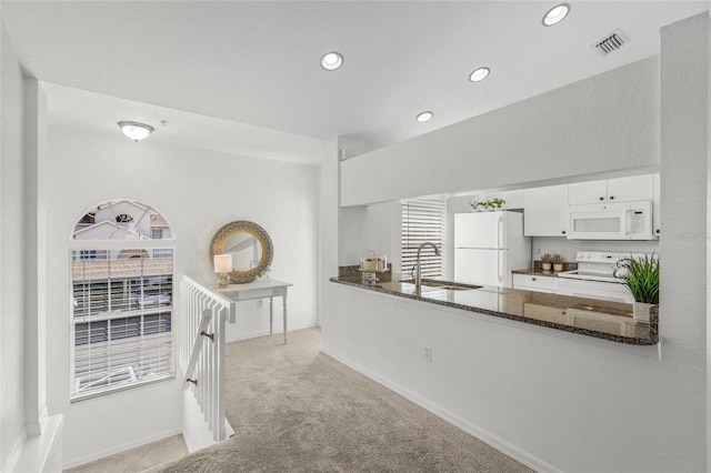 kitchen featuring sink, white appliances, white cabinetry, dark stone countertops, and light colored carpet