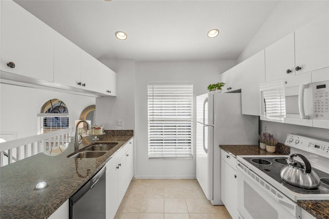 kitchen featuring white cabinetry, sink, dark stone counters, light tile patterned floors, and white appliances