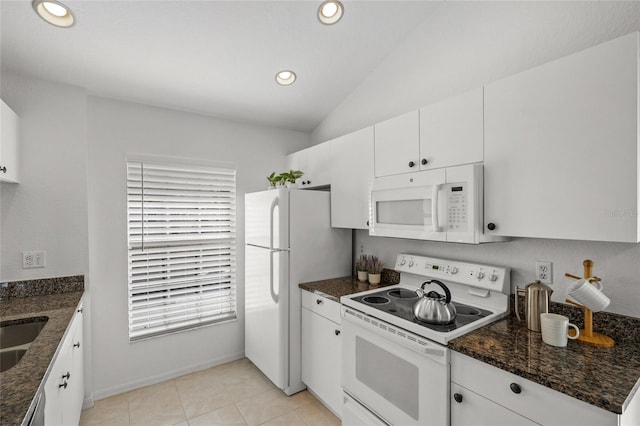 kitchen featuring white cabinetry, vaulted ceiling, dark stone countertops, and white appliances