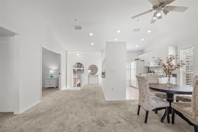 carpeted dining space featuring high vaulted ceiling and ceiling fan