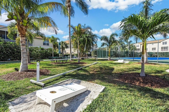 view of property's community with a yard and tennis court