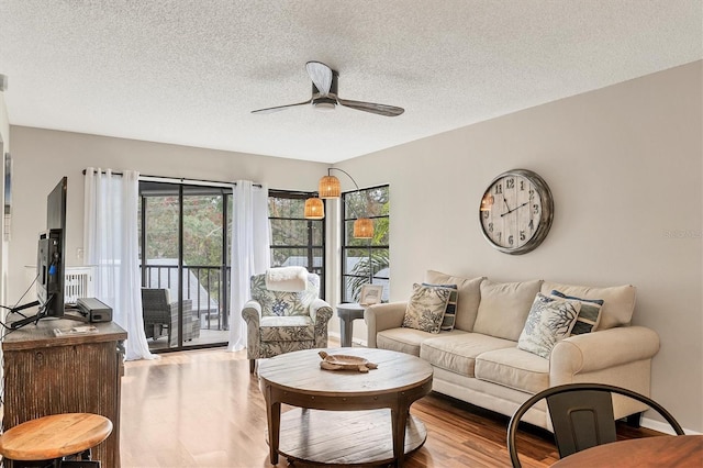 living room featuring a textured ceiling, ceiling fan, and light hardwood / wood-style flooring