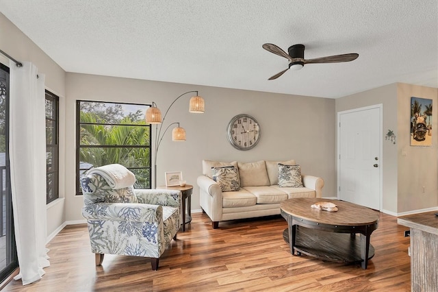 living room featuring ceiling fan, wood-type flooring, and a textured ceiling