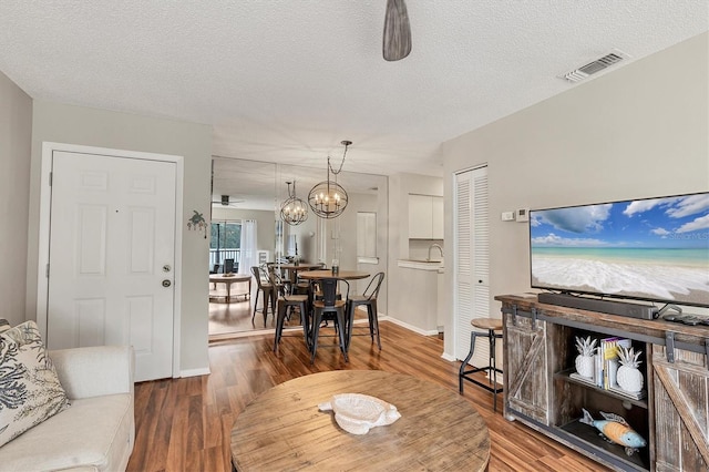 living room featuring ceiling fan with notable chandelier, hardwood / wood-style floors, and a textured ceiling