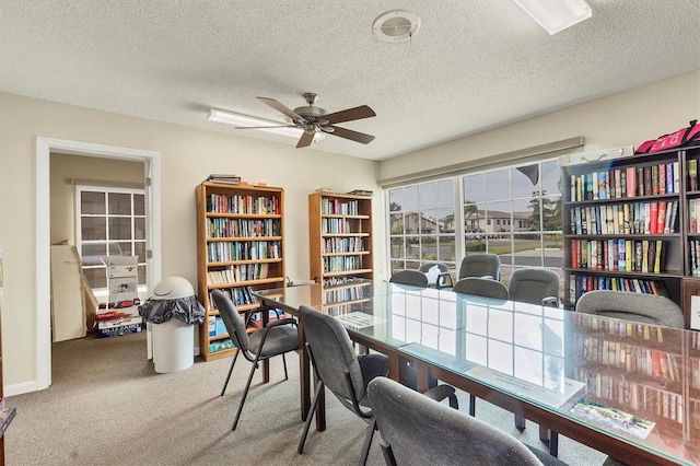 carpeted office space with ceiling fan and a textured ceiling