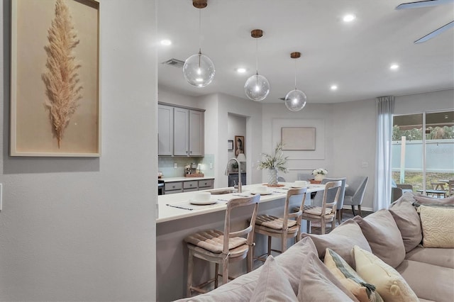 kitchen with pendant lighting, sink, gray cabinets, a breakfast bar, and decorative backsplash