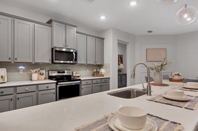 kitchen featuring sink, gray cabinets, stainless steel appliances, decorative backsplash, and decorative light fixtures