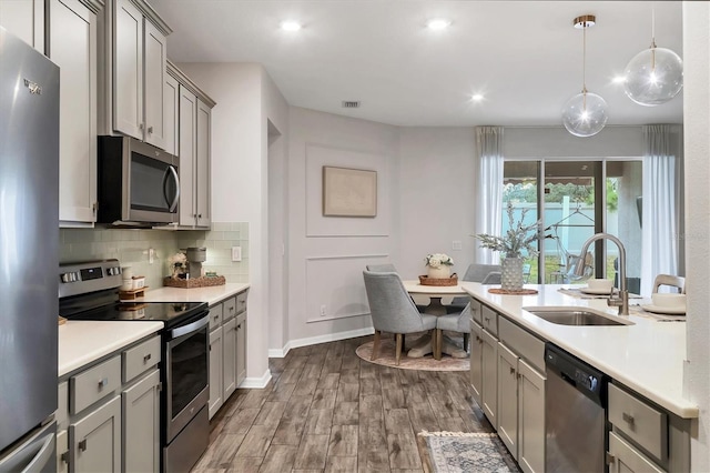 kitchen featuring sink, tasteful backsplash, decorative light fixtures, gray cabinets, and stainless steel appliances