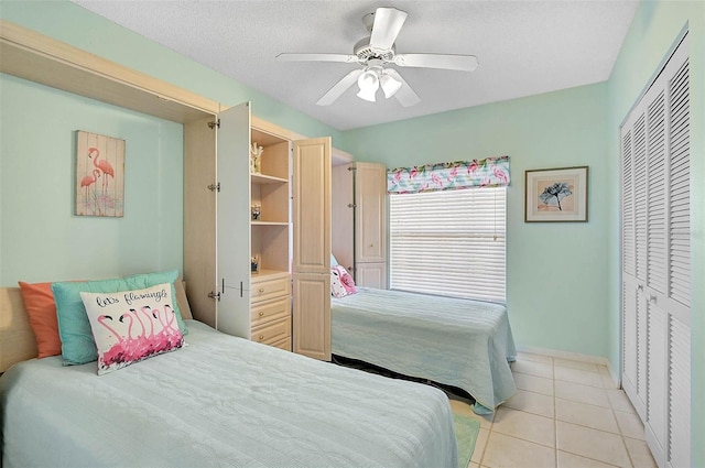 bedroom featuring ceiling fan, a closet, a textured ceiling, and light tile patterned floors