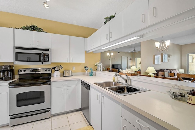 kitchen featuring sink, white cabinetry, stainless steel appliances, light tile patterned flooring, and ceiling fan with notable chandelier