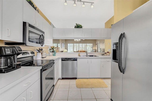 kitchen with appliances with stainless steel finishes, sink, light tile patterned floors, and white cabinets