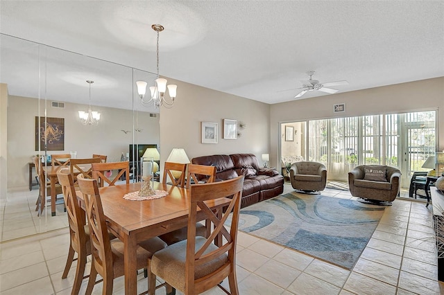 tiled dining room featuring ceiling fan with notable chandelier and a textured ceiling