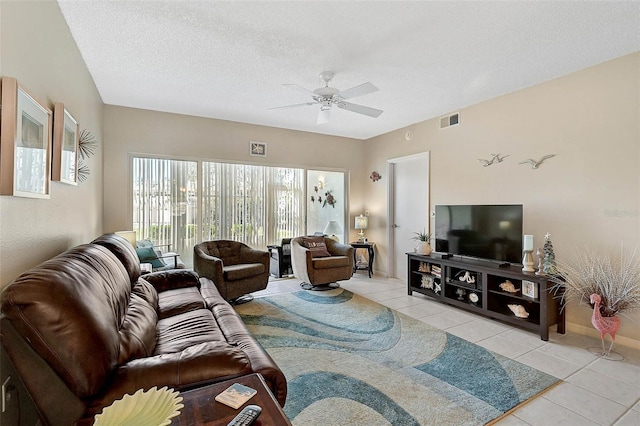 living room with ceiling fan, light tile patterned floors, and a textured ceiling