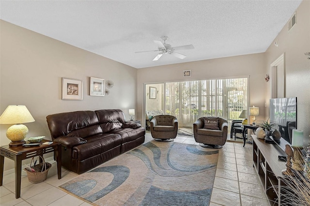 living room with ceiling fan, a textured ceiling, and light tile patterned floors