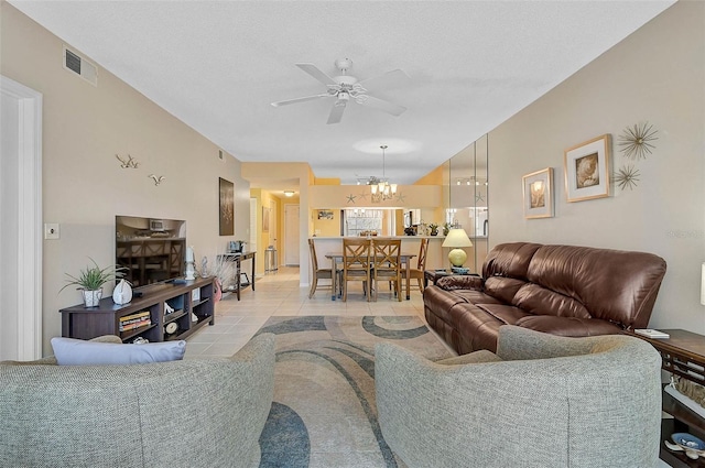 tiled living room with ceiling fan with notable chandelier and a textured ceiling