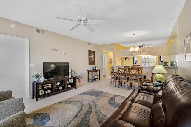 living room with ceiling fan with notable chandelier, light tile patterned floors, and a textured ceiling