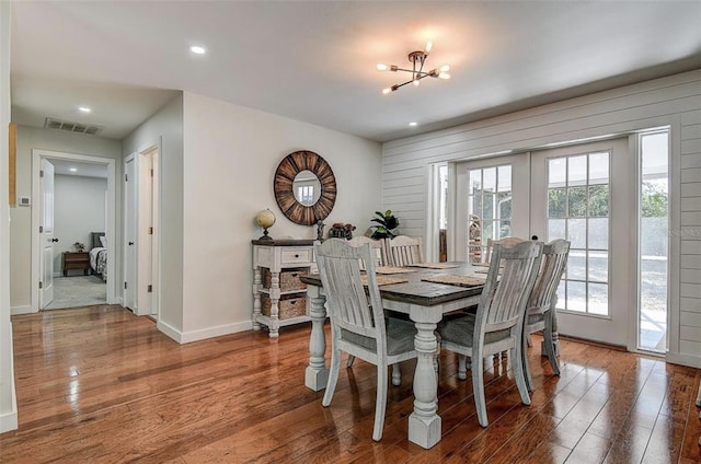 dining area with hardwood / wood-style flooring, an inviting chandelier, and french doors