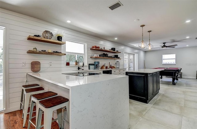 kitchen with a breakfast bar area, pool table, hanging light fixtures, kitchen peninsula, and ceiling fan