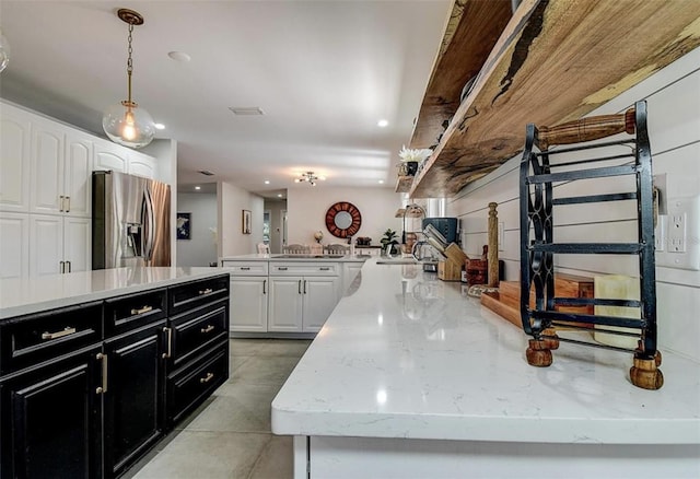 kitchen featuring light stone counters, stainless steel fridge, white cabinets, and a kitchen island