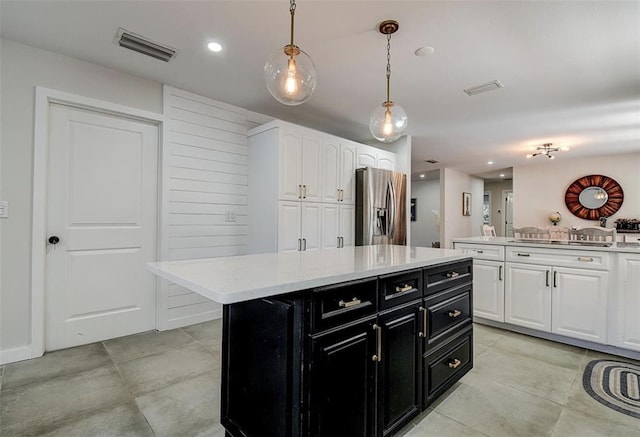 kitchen with pendant lighting, stainless steel fridge, a kitchen island, and white cabinets