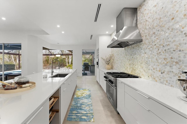 kitchen with a sink, ventilation hood, decorative backsplash, stainless steel range, and modern cabinets