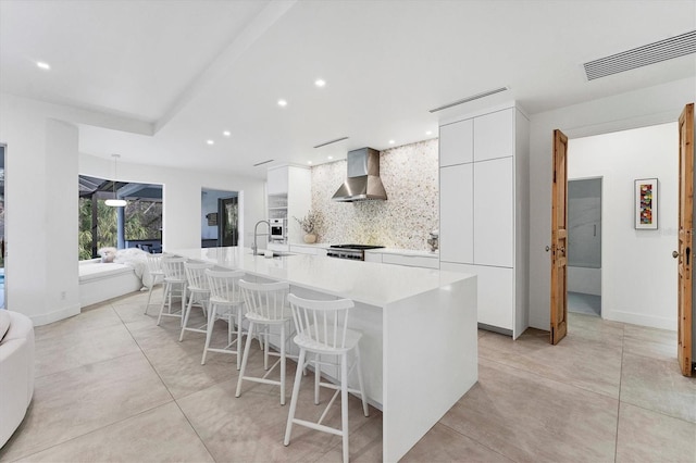 kitchen featuring visible vents, range, decorative backsplash, wall chimney exhaust hood, and modern cabinets