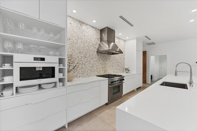 kitchen featuring white oven, high end stainless steel range, white cabinets, wall chimney range hood, and modern cabinets