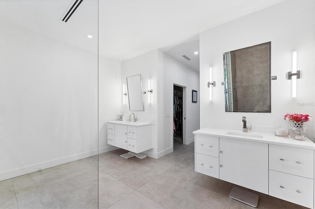 bathroom featuring a spacious closet, two vanities, a sink, and baseboards