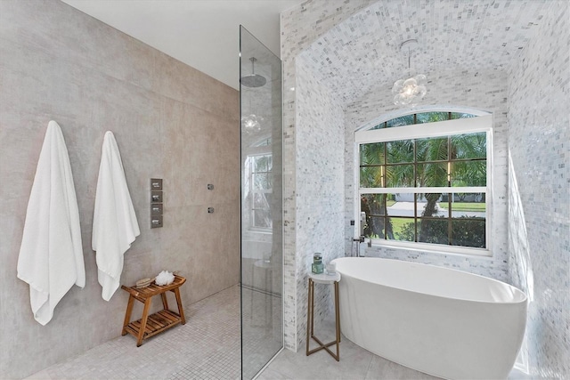 bathroom with a freestanding tub, walk in shower, tile walls, and tile patterned floors