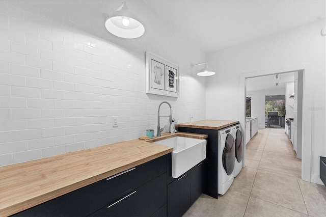 laundry area with light tile patterned floors, separate washer and dryer, and a sink