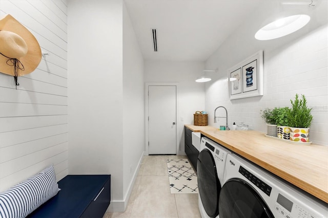 washroom with washer and clothes dryer, light tile patterned flooring, a sink, laundry area, and baseboards