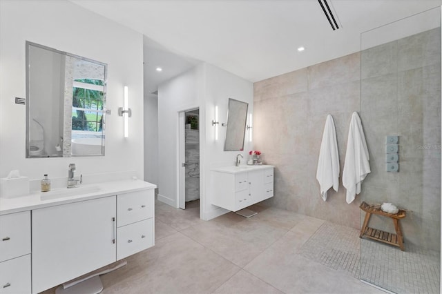 full bathroom featuring recessed lighting, two vanities, a sink, tile walls, and walk in shower