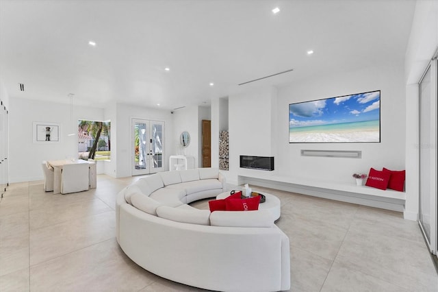 living area with a glass covered fireplace, french doors, light tile patterned flooring, and recessed lighting