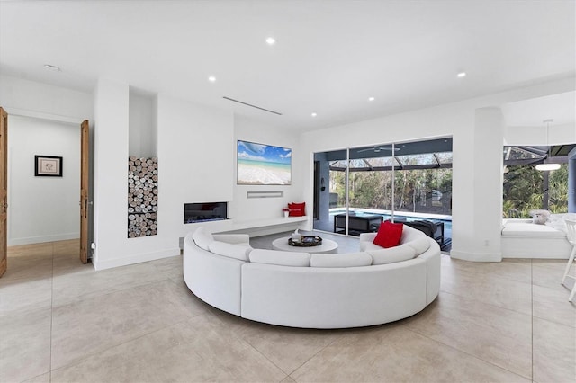 living room with recessed lighting, a sunroom, a glass covered fireplace, and baseboards