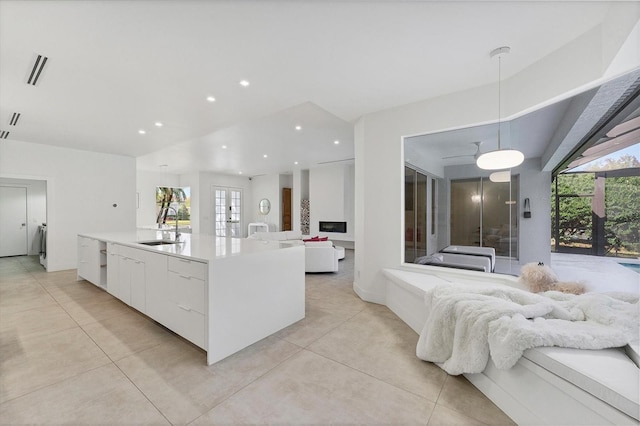 kitchen featuring white cabinets, modern cabinets, open floor plan, hanging light fixtures, and a sink