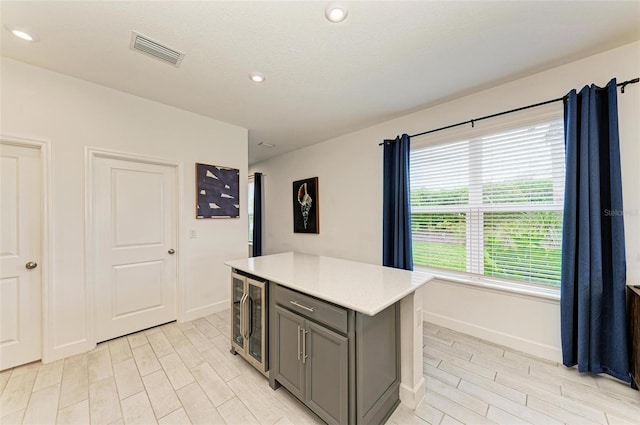 kitchen featuring a kitchen island, gray cabinetry, and wine cooler