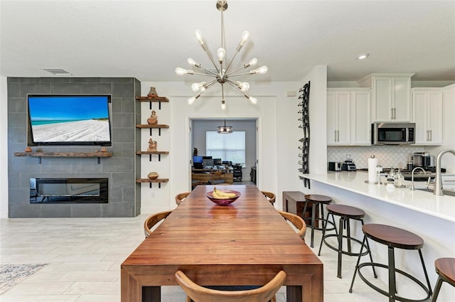 dining room with an inviting chandelier and a tile fireplace