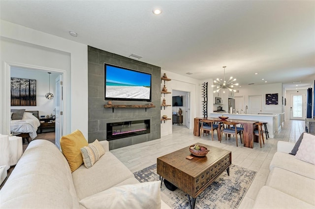 living room with a tiled fireplace, a notable chandelier, and a textured ceiling