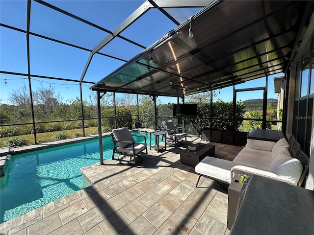 view of pool with a patio, glass enclosure, and an outdoor living space with a fire pit