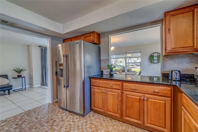 kitchen featuring high end fridge, tasteful backsplash, light tile patterned floors, a tray ceiling, and dark stone counters