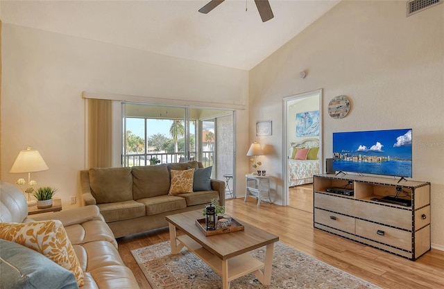 living room with ceiling fan, high vaulted ceiling, and light wood-type flooring