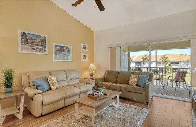 living room with ceiling fan, high vaulted ceiling, and light wood-type flooring