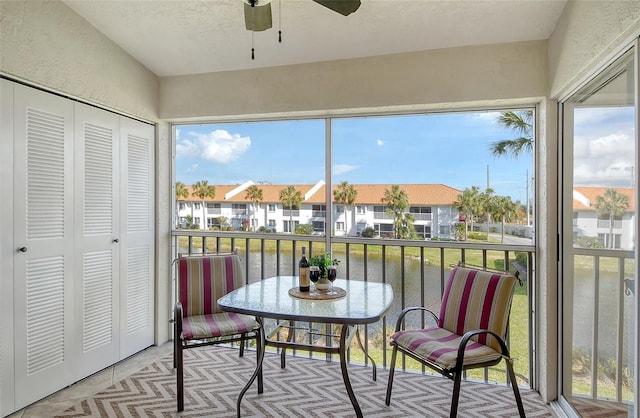 sunroom featuring ceiling fan and a water view