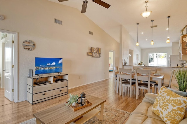 living room featuring light hardwood / wood-style flooring, high vaulted ceiling, and ceiling fan